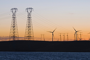 Wind turbines and power transmission lines at sunset near San Francisco