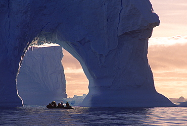 Boating by an iceberg arch near Yalour Islands, Antarctica.