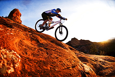 A middle age man rides his mountain bike through the red rock country around Sedona, Az at sunset.