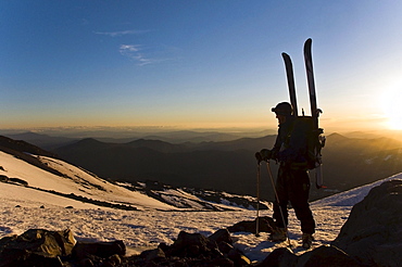 A ski mountaineer takes in the view while climbing Mount Shasta at sunrise, CA.