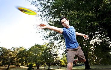 Closeup of a man making a backhanded drive playing disc golf. (Motion Blur)