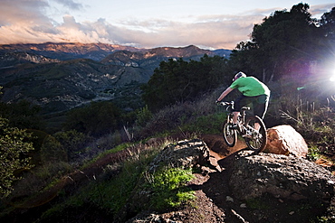 A young man rides his downhill mountain bike on Knapps Castle Trail, surrounded by beautiful scenery in Santa Barbara, CA.