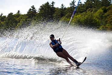 A female water skier rips a turn causing a huge water spray while skiing on Cobbosseecontee Lake near Monmouth, Maine.