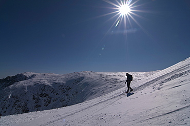 Hiker heading downhill in the winter sunshine.