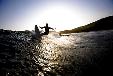 A male surfer does a turn while riding a wave at Leo Carrillo State Park in Malibu, California.