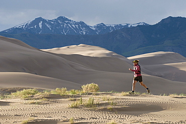 Woman running through sand dunes, Great Sand Dunes National Park, Alamosa, Colorado.