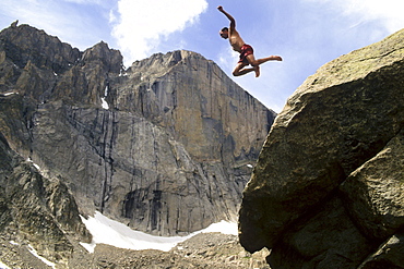 Man jumping off rock below Long's Peak, Rocky Mountain National Park, Estes Park, Colorado.