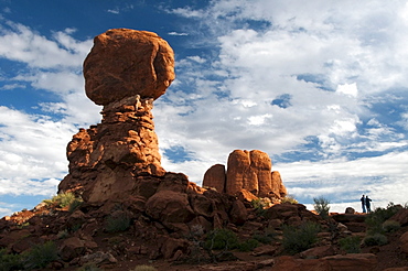 Two hikers admire Balanced Rock in Arches National Park, Utah.