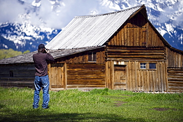 A photographer takes a picture of a historic barn on Mormon Row in Grand Teton National Park, Wyoming.