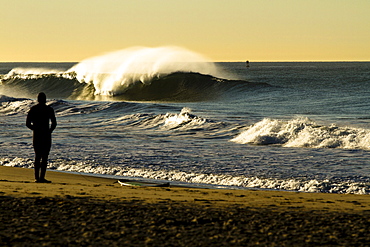 A surfer attaches his leash while watching a large clean wave break in Oxnard, California on January 4, 2012.