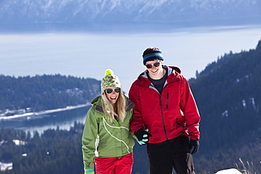 Two young adults smile while snowshoeing on a beautiful winter day in Sandpoint, Idaho.