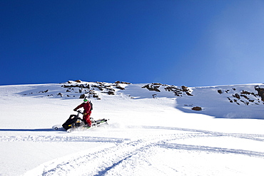 A athletic young man snowmobiling high marks on a untracked mountain in Cooke City, Montana.