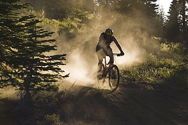 A man mountain biking in the dust.