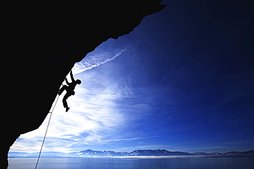 Man climbing against blue sky.