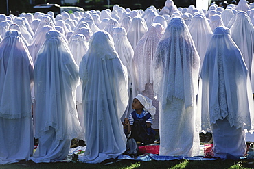 Javanese Moslem women gather for a celebration marking the end of Ramadan in Paramaribo, the captial of Suriname. A young girl waits for her mother and the other women to end their prayers.