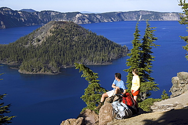 Hikers along cliff trail near lake.