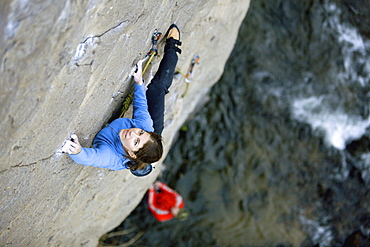 Two people climbing above river