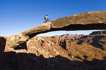 Mountain biker crossing sandstone bridge, Canyonlands, Utah (fisheye lens).