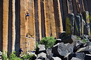 A young woman rock climbing while a mid adult man belays at Trout Creek, Oregon.