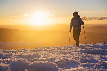 Female hiker at sunrise on winter summit of Pen Y Fan, Brecon Beacons national park, Wales