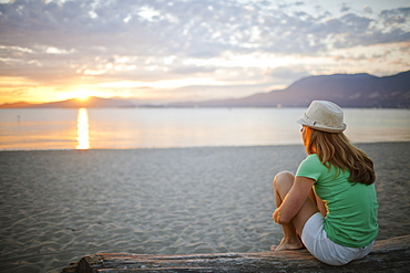 A woman watches the sunset from Kit's Beach, Vancouver Canada.