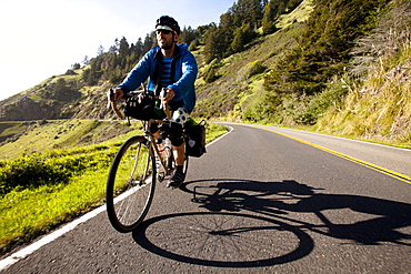 A male cyclist rides his touring bike down the Pacific Coast Highway near Jenner, California on April 12, 2013.