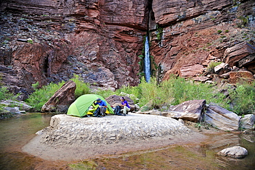 Hikers setup camp on a beach along the Colorado River near the plumeting 180-foot Deer Creek Falls in the Grand Canyon outside of Fredonia, Arizona November 2011.  The 21.4-mile loop starts at the Bill Hall trailhead on the North Rim and descends 2000-feet in 2.5-miles through Coconino Sandstone to the level Esplanada then descends further into the lower canyon through a break in the 400-foot-tall Redwall to access Surprise Valley.  Hikers connect Thunder River and Tapeats Creek to a route along the Colorado River and climb out Deer Creek.