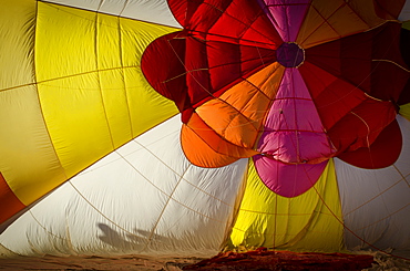 Crews work carefully, inflating their hot air balloons for launch. The Albuquerque International Balloon Fiesta takes place in Albuquerque, New Mexico each year drawing in participants and spectators from across the globe. Highlights include an early morning dawn patrol, followed by mass ascencion of aircraft and an evening glow which all take place at the Balloon Fiesta Park throughout the week long event.