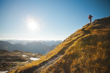 A hiker follows a footbed to the top of a mountain ridge, North Cascades National Park, Washington, United States