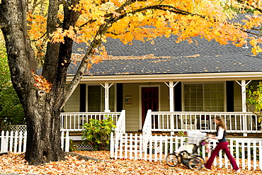 Mother pushing stroller in front of victorian house with fall leaves, Nevada City, California, Nevada City, California, USA