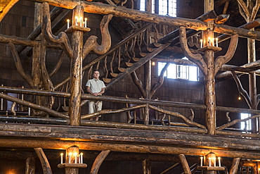 A woman standing next to the intricate logwork inside the Old Faithful Lodge in Yellowstone National Park, Wyoming, Yellowstone, Wyoming, usa