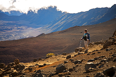 A woman in her thirties carrying an infant hikes in the high-elevation volcanic Haleakala crater, Maui, Hawaii, United States of America