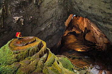 A cave explorer on a speleothem at the first doline, or skylight, in Hang Son Doong while two other explorers illuminate a large passage leading to the second doline 1.5 kilometers away.