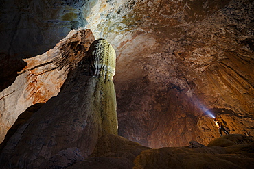 A cave explorer stands beside a large stalagmite in Hang Son Doong, Vietnam.