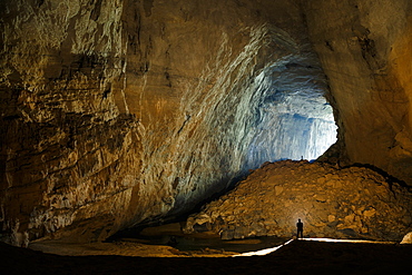 Cave explorers illuminate a large passage in Hang En, Phong Nha Ke Bang National Park, Vietnam.