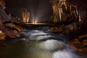 A cave explorer crosses a fast flowing river in Hang Son Doong, Vietnam