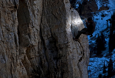 Man rappels in the dark by headlamp.