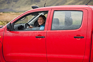 Woman driving red pick up truck in Iceland