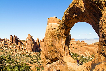 A man standying in Double O arch as he looks at the horizon at the Arches National Park in Utah near Moab.