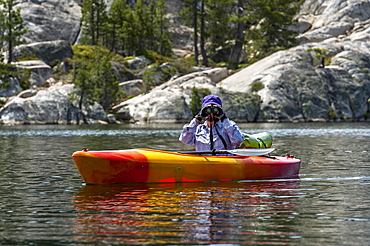 A woman looking through her binoculars while birding at Utica Reservoir.