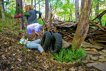 A girl jumps over a boy at their make shift hut in the woods at Pittsburgh PA. during the spring