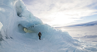 A man exploring an iceberg frozen into the surface of the McMurdo Sound in the Ross Sea Region of Antarctica.