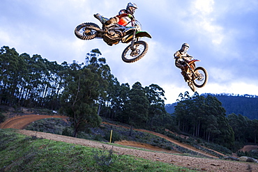 Two dirt bike riders jump a tabletop at the same time during a race at Blackwood park.