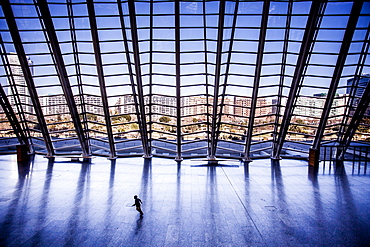 Child running across an empty floor at a museum.