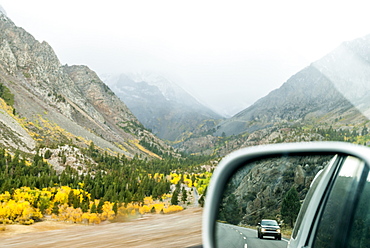 Side mirror view driving up Tioga Pass in a storm