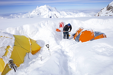 A mountain ranger is digging out tents after a snowstorm covered them during the night in 14k camp on Mount McKinley, Alaska.     Climbers are advised to spare no expense on a expedition-quality tent as it can mean the difference between life and death during a ferocious storm on Denali.     Extra poles and repair materials are important in case of damage caused by storms. Plan to take extra pickets, wands or deadmen for tent anchors. Never leave a tent without anchoring it securely. Tents are lost each year due to sudden gusts of wind while the tent was left unattended or drying.     Every climbing season High Mountain Rangers of the Denali National Park Service are called to help climbers in need. If possible the patient is brought down to base camp on foot, only in life threatening conditions a helicopter is called to evacuate the patient to a hospital in Anchorage.