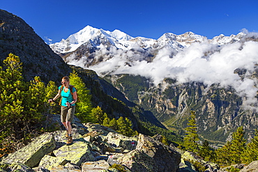 A female hiker on her way to the Wannihorn, a mountain peak in the Swiss Alps, close to Zermatt. In the background is the Weisshorn range. This region of Wallis is home to over 40 of 4000 meter peaks and a paradise for outdoor enthusiasts like climbers, hikers, mountainbikers, trailrunners and nature lovers.