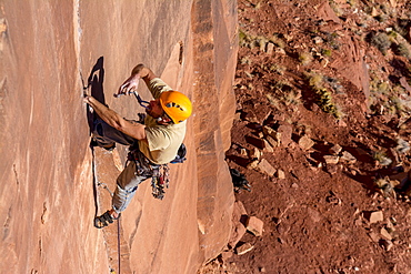 A man rock climbing up a difficult crack called Sig Sauer at the Pistol Whipped Wall in Indian Creek, Monticello, Utah.