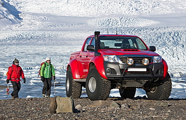 2 climbers hiking back to customised SUV / Icelandic superjeep / 4x4 pick up truck