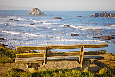 An old weathered wooden bench looks out at Bandon Bay, Oregon.